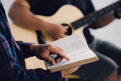 Male adults are reading the Holy Scriptures pointing to the characters.And befriends playing guitar, The books of the Bible, Concepts of Christianity.