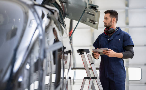 Male Aero Engineer With Clipboard Checking On Helicopter In Hangar stock photo