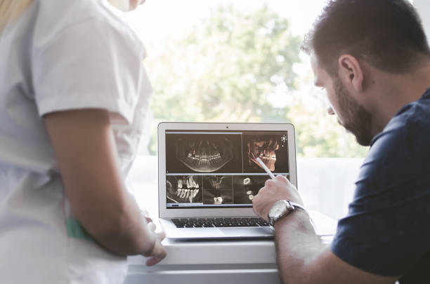 Male and female dentist looking at xray Male dentist explaining dental Xray to female assistent in clinic. human jaw bone stock pictures, royalty-free photos & images