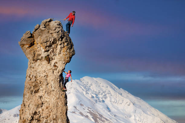 Male and female rock climbers with the lead that secures the partner stock photo