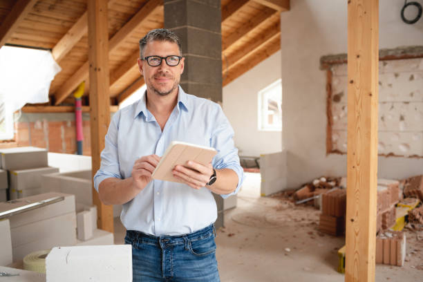 male architect with black glasses stands on construction site in loft house and holds his tablet stock photo