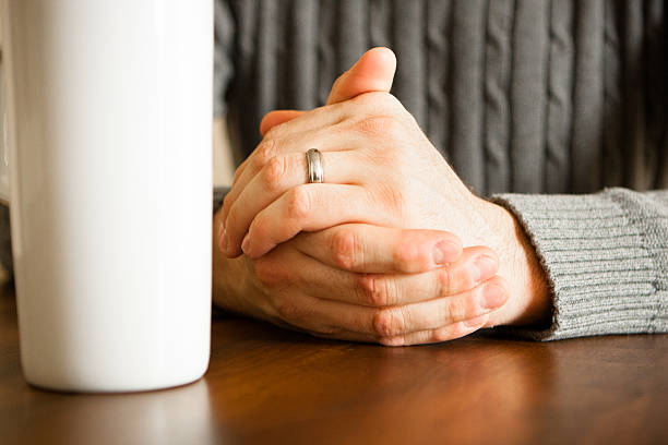 Male at Table, Hands folded with coffee mug stock photo