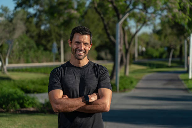 Male athlete on the street in the park, posing for a corporate portrait, close-up, for promotion as a fitness trainer. Crossed arms stock photo