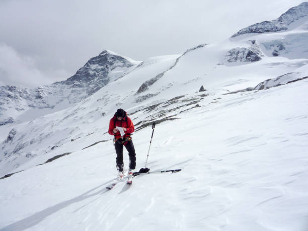 male backcountry skier studies a map on a high alpine glacier in the Austrian Alps backcountry skier mountain guide looking at a map in the high alpine mountains of Austria in the Hohen Tauern region while guiding a group of clients osttirol stock pictures, royalty-free photos & images