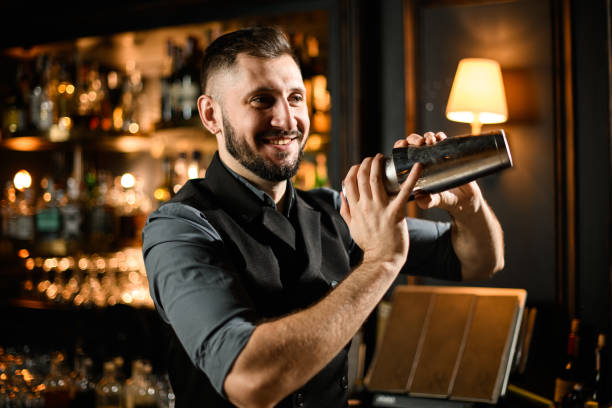 male bartender shakes cocktail in stainless steel shaker - ready mix imagens e fotografias de stock