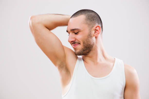 Male beauty Young man is smelling his armpit after shower. shaved armpits stock pictures, royalty-free photos & images