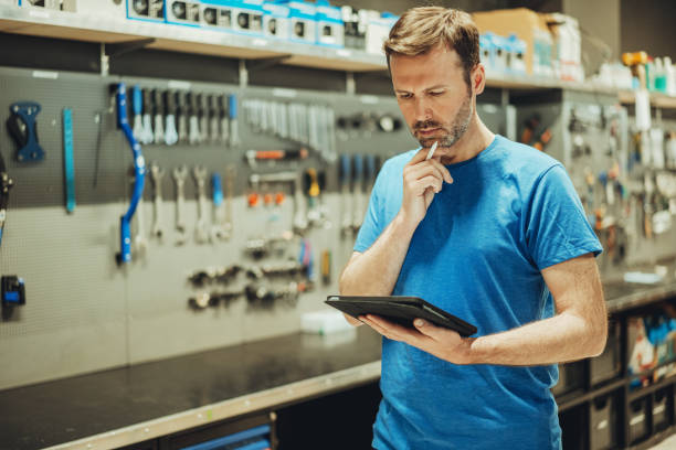 male bicycle mechanic checking with tablet a bicycle in his workshop stock photo