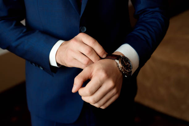 Male businessman dresses and adjusts his watch, preparing for a meeting. Clock stock photo