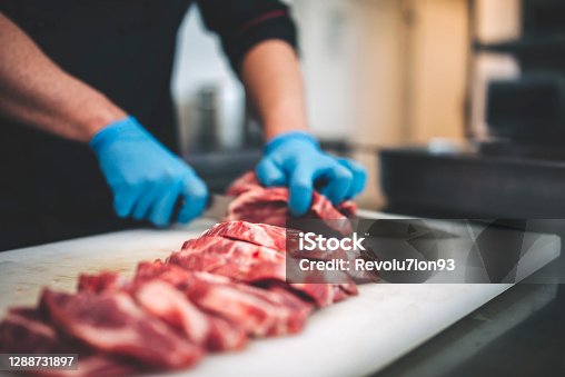 istock Male butcher cut raw meat with sharp knife in restaurants kitchen 1288731897