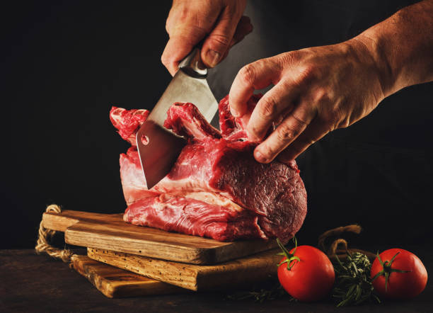 Male butcher cuts raw beef meat. stock photo