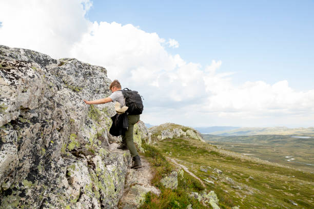A male climbing on rocks while hiking in the Norwegian nature stock photo