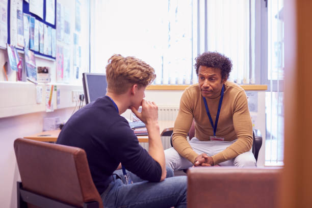 Male College Student Meeting With Campus Counselor Discussing Mental Health Issues Male College Student Meeting With Campus Counselor Discussing Mental Health Issues school counselor stock pictures, royalty-free photos & images