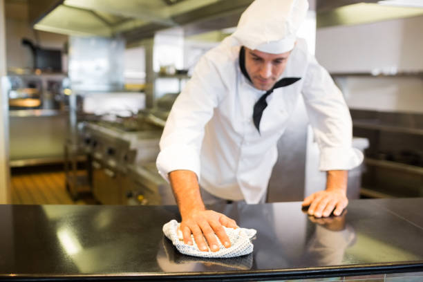 Male cook wiping the kitchen counter Male cook wiping the counter top in the kitchen restaurant cleaning stock pictures, royalty-free photos & images