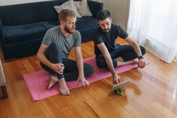 coppia maschile che guarda video di yoga a casa - correa foto e immagini stock