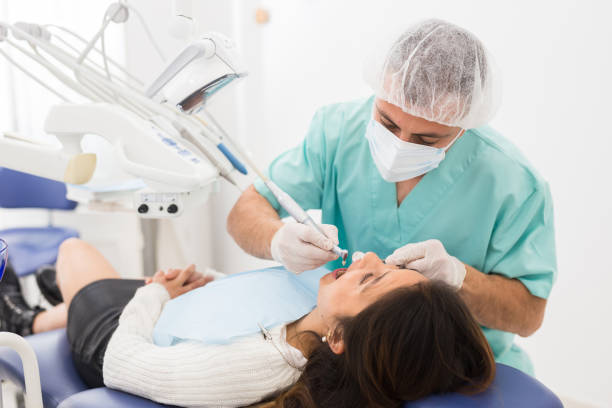 Male dentist drilling tooth to female patient stock photo
