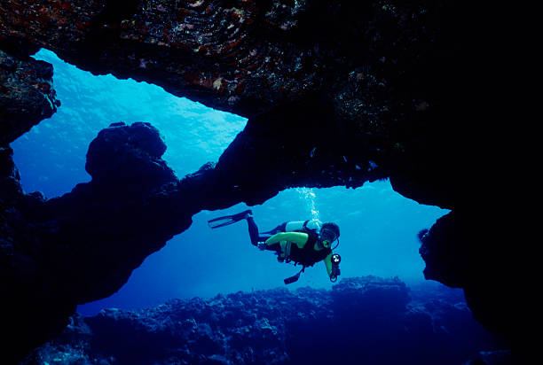 Male Diver in Underwater Cave Diver swimming through blue  underwater cavern. deep sea diving stock pictures, royalty-free photos & images