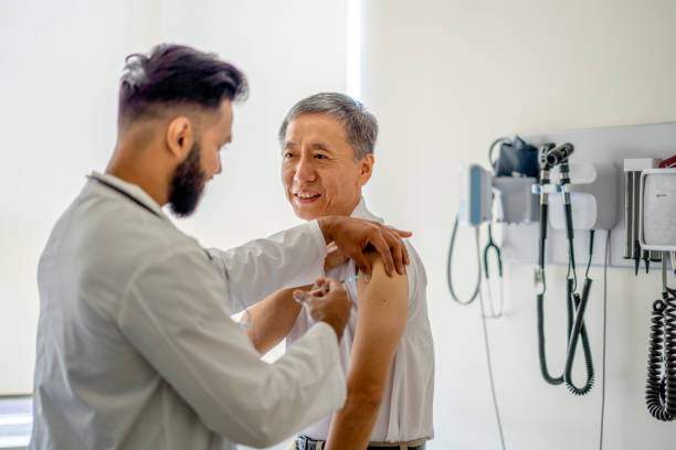 Male doctor administers medical injection into senior patient's arm stock photo