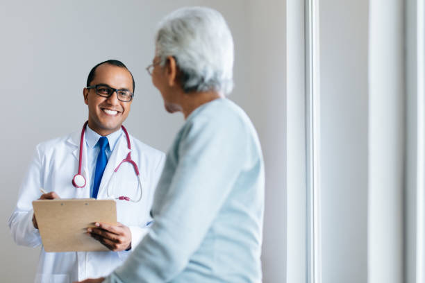 Male doctor checking senior female patient and smiling stock photo
