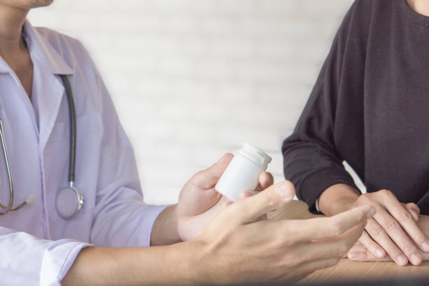manliga läkare att ge flaska medicin till kvinnlig patient på ett sjukhus - två burkar piller bildbanksfoton och bilder