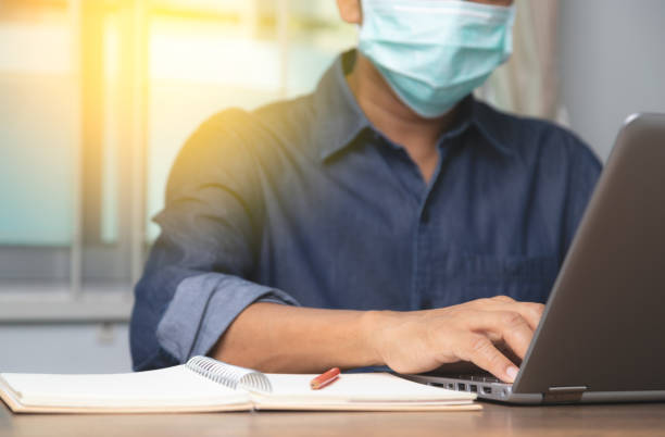 Male employee wearing a health mask Preventing corona virus infection covid-19, concept of working from home and social distancing. Male employee wearing a health mask Preventing corona virus infection covid-19, concept of working from home and social distancing. effort photos stock pictures, royalty-free photos & images