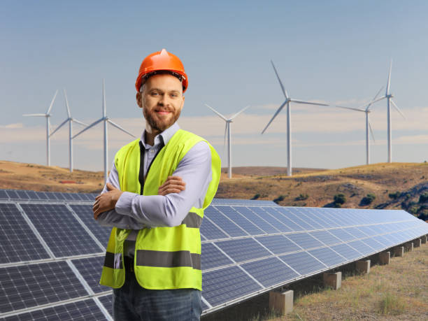 Male engineer with a safety vest standing on a wind and solar farm stock photo