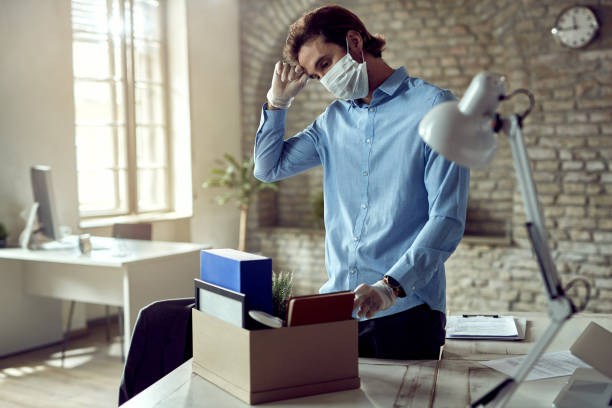 Male entrepreneur losing his job due to coronavirus epidemic. Young sad businessman packing his belongings after being fired during COVID-19 pandemic. unemployment photos stock pictures, royalty-free photos & images