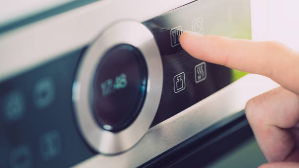 Male finger is touching the button of modern panel of electric oven. stock photo