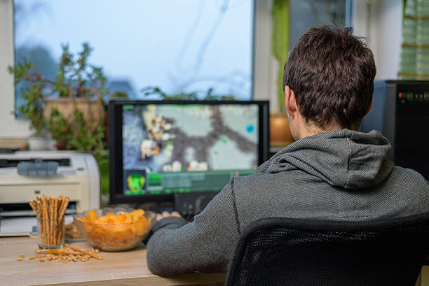 male gamer playing strategy game on computer eating snacks male gamer playing strategy game on computer with snacks lying on table - stock photomale gamer playing strategy game on computer with snacks lying on table - stock photomale gamer playing strategy game on computer with snacks lying on table - stock photo freeadultvideos stock pictures, royalty-free photos & images