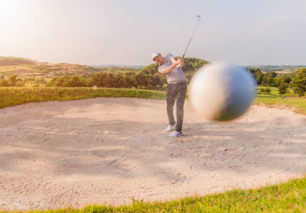 Male golfer shoting golf ball from sand bunker stock photo