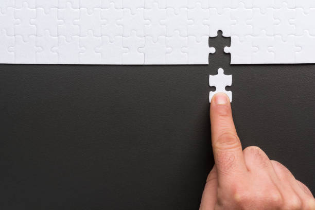 Male hand holds the last piece of the puzzle stock photo