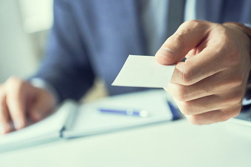 male hand in suit give blank calling card to visitor