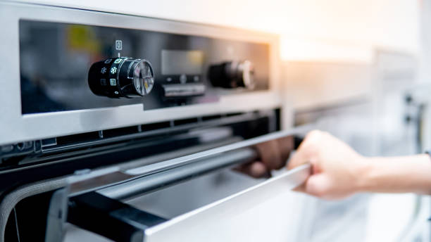 Male hand opening oven door Male hand opening oven door in the kitchen showroom. Buying cooking appliance for domestic kitchen. Home improvement concept oven stock pictures, royalty-free photos & images