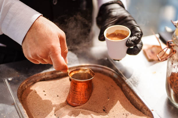 male hand preparing Turkish coffee in burning sand at Souq Waqif Male hand preparing Turkish coffee in burning sand at Souq Waqif, Doha, Qatar souk stock pictures, royalty-free photos & images