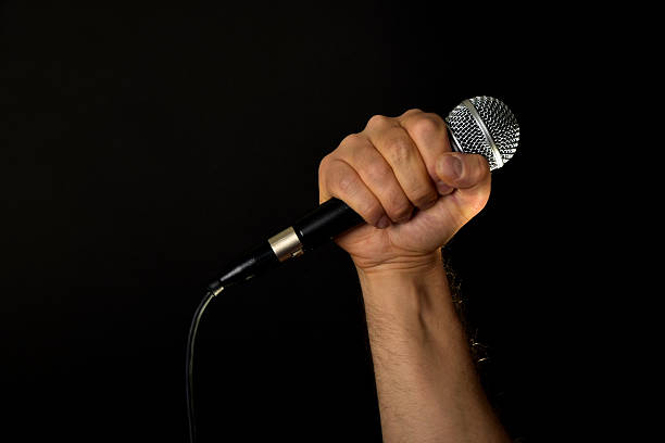 Male hand with microphone isolated on black stock photo