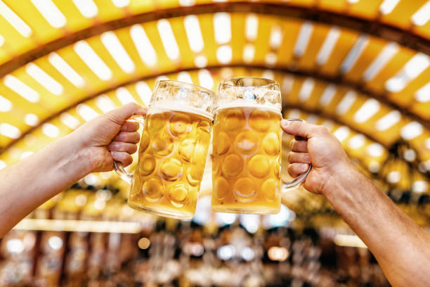 mannelijke handen rammelende bierglazen op oktoberfest in münchen - duits bier stockfoto's en -beelden