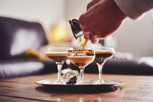 Male hands pouring espresso martini cocktail into glass