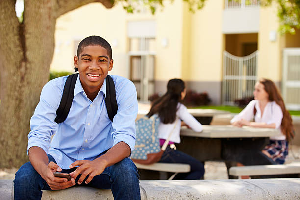 male high school student using phone on school campus - alleen één tienerjongen stockfoto's en -beelden