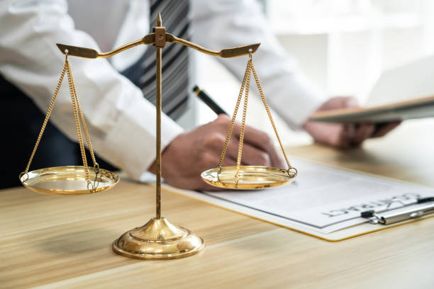 Male lawyer or jurist working with litigation contract paper documents of the estate lawsuit, Law books and wooden gavel on table in office stock photo
