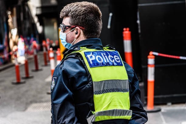 A male member of Victoria Police stands watch at a hotel quarantine site stock photo