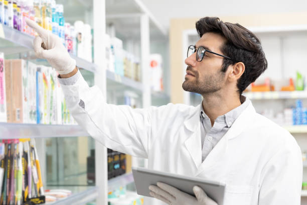 pharmacien masculin vérifiant la pharmacie de stock utilisant la technologie numérique de tablette dans la pharmacie moderne. - pharmacien photos et images de collection
