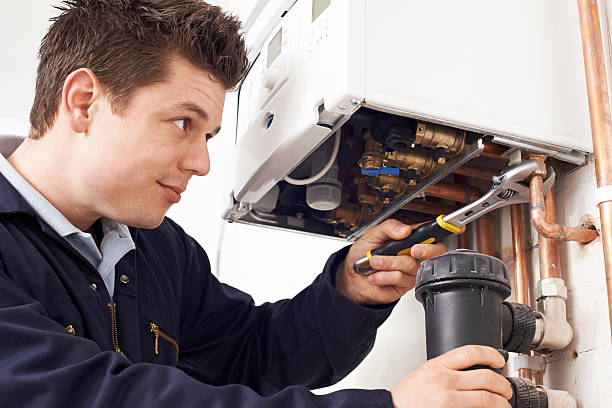 Male Plumber Working On Central Heating Boiler stock photo