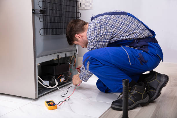 Male Repairman Checking Fridge With Digital Multimeter Side View Of A Male Repairman Checking Refrigerator With Digital Multimeter At Home Refrigerator Repair stock pictures, royalty-free photos & images