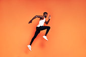 istock Male runner doing fitness workout. Athlete exercising over an orange background. 1334140079