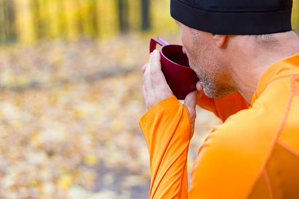 Male runner drining from plastic thermos cup stock photo