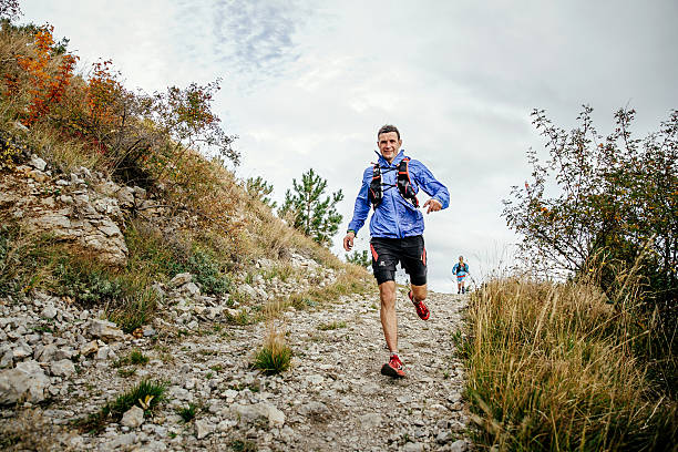 male runner of middle age runs on a mountain trail stock photo