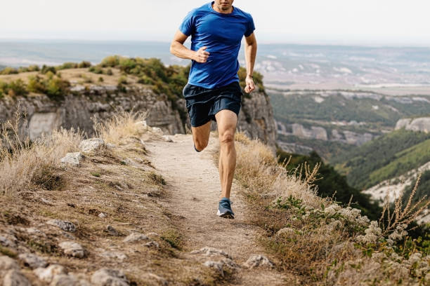 male runner running male runner running mountain trail on edge of cliff cross country running stock pictures, royalty-free photos & images