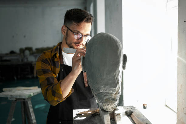 Male Sculptor working on a clay bust Male Sculptor finishing a clay bust sculpture stock pictures, royalty-free photos & images