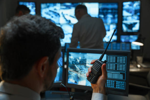 A male security guard in the security room keeps order with the help of modern technologies. The security service monitors display all the information from the surveillance cameras. stock photo