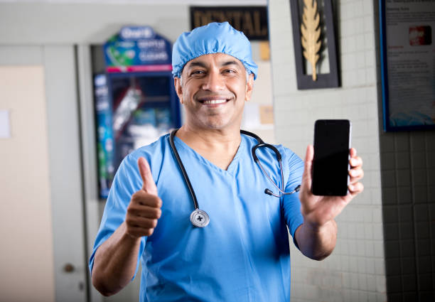 manlig kirurg som visar mobiltelefon - happy scrubs nurse phone bildbanksfoton och bilder