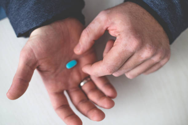 Male taking blue pills from hands close up White man taking the blue pill from the table, close up on hands and pill. The pill can be used as viagra or medicine for some skin diseases anti impotence tablet stock pictures, royalty-free photos & images